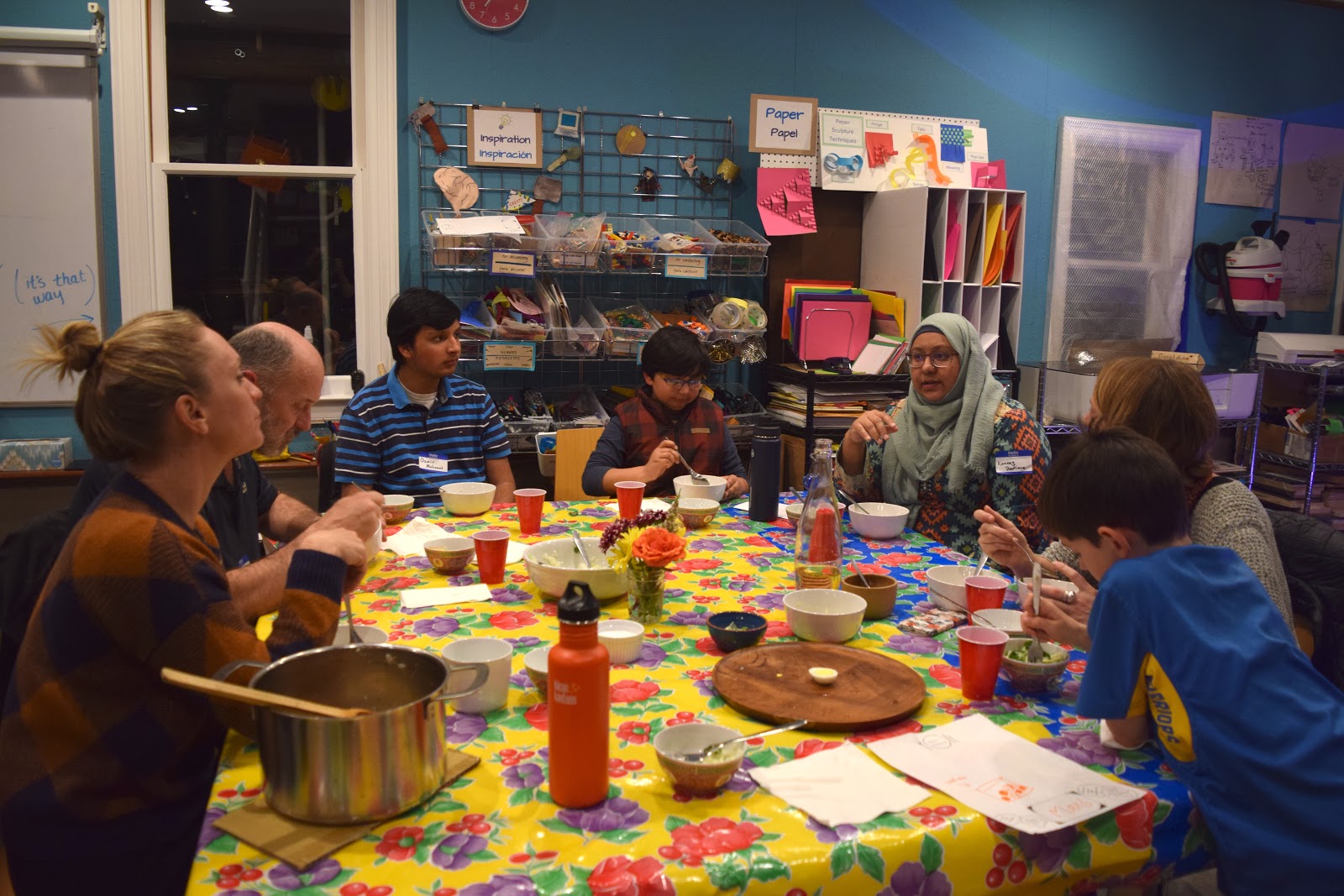 A photograph of a group of people enjoying a meal together at the Maker Ed Community Studio. 