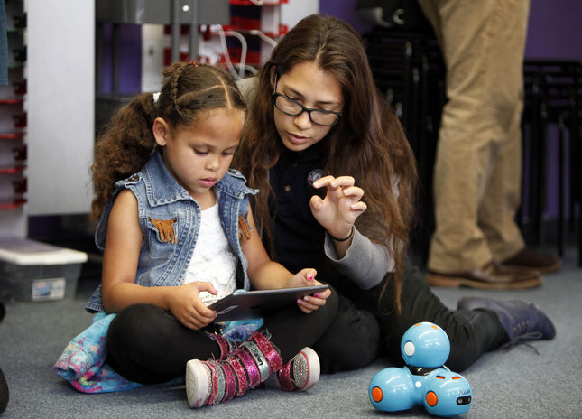 Jayla Bryan-Smith, 7, and Montana Manalo of Americorps, play with an iPad-controlled robotics device at Brentwood School in East Palo Alto, Calif., where students showed off their Makerspace classroom on Monday, May 15, 2015. The classroom is outfitted with laptops and printers donated by Facebook in an initiative to provide students with STEM opportunities. (Karl Mondon/Bay Area News Group)